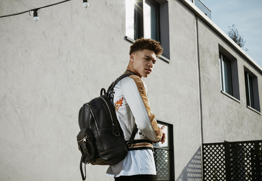 Brian Whittaker wears the Coach Snake and Star Souvenir Jacket and Coach Flag Backpack in black pebble leather.